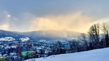 Çok güzel bir kış manzarası var. Karlı dağlar aşağıdaki canlı bir kasabanın tepesinde yükseliyor.