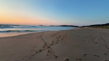 Güzel ve dingin bir sahil sahnesi, dalgalar sergiliyor kıyıya vuruyor ve nefes kesici bir gün batımı.