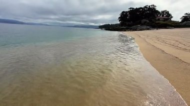 Sakin bir sahil, kumlu sahilde hafif dalgalar, rahatlama ve huzur için ideal bir atmosfer yaratıyor.