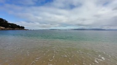 Güzel, sakin bir sahil sahnesi. Hafif dalgalar, geniş kumlu kıyılar ve yukarıda resim gibi bir gökyüzü.