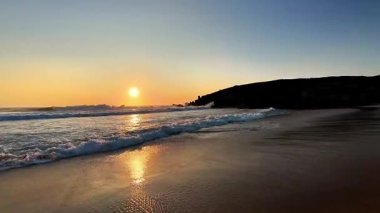 Nefes kesici ve çarpıcı bir gün batımı güzel yansımasını sakin bir kumsalın nazik dalgalarına fırlatır.