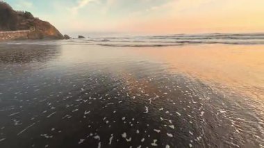 Zarif okyanus dalgalarının güzel sakin manzarası muhteşem renkli günbatımı gökyüzünün altında zarifçe yuvarlanıyor.