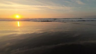 Nefes kesen bir günbatımı, huzurlu sahil sularına renklerini salıyor ve güzel, huzurlu bir sahil manzarası yaratıyor.