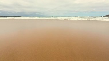 Huzurlu ve sakin bir sahil sahnesi yumuşak, sıcak altın kum üzerinde zarif dalgaların yuvarlandığı.