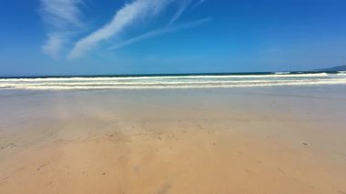 Huzurlu bir sahil manzarası yumuşak, altın kumlar ve nazikçe dalgalanan okyanus dalgaları, nihai rahatlama için mükemmel