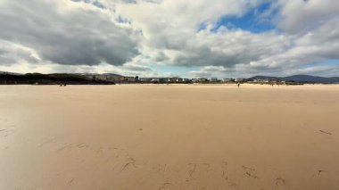 Nefes kesen bir plaj sahnesi, hafif dalgaları tasvir eder canlı, berrak bir mavi gökyüzüne karşı.