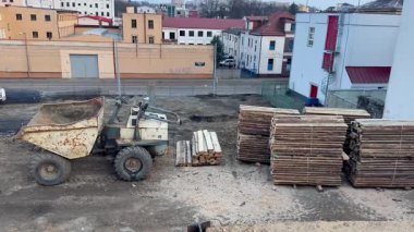 Büyük bir çöp kamyonu ve düzenli bir kütük yığını barındıran hareketli bir inşaat alanı