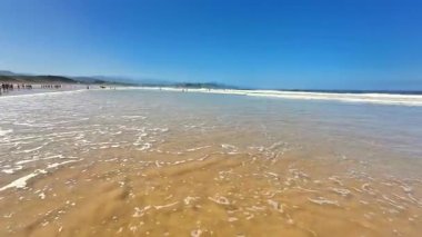 Güzel bir sahil manzarası, güneşli bir günde hafif dalgalarla yavaşça kıyıya vurur.