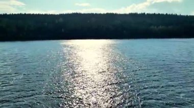 Bu huzurlu sahnede, dingin bir göl güzel, berrak gökyüzünü ve kayan tepeleri mükemmel bir şekilde yansıtır.