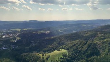 Yeşil dağların ve yuvarlanan tepelerin çarpıcı hava perspektifi, doğanın sükunetini yakalıyor..