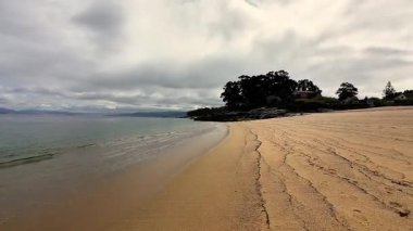 Huzurlu bir sahil sahnesi yumuşak altın kumları, yumuşak dalgaları ve doğanın sükunetini gözler önüne seriyor.
