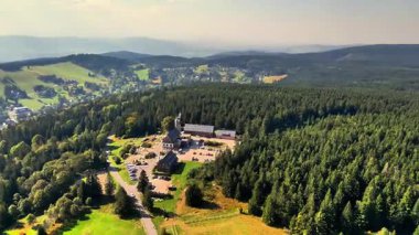 Çarpıcı bir manzara bulutlu bir gökyüzünün altındaki doğal güzellikleri gösteren yuvarlanan tepeleri ve vadileri vurguluyor.