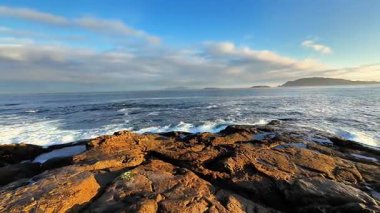 Engin okyanusla canlı bir gökyüzünün altında zarif bir şekilde buluşan kayalık kıyı şeridinin nefes kesici bir görüntüsü.