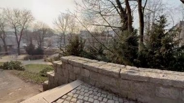 Güzellik içinde büyüleyen eski bir taş duvar, huzur dolu bir parkta yemyeşil ağaçlarla çevrili, doğal cazibesini sergiliyor.