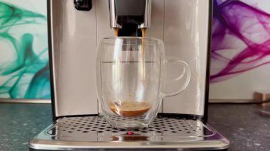 Modern bir kahve makinesi şık bir cam fincanda zengin espresso demler, kahve deneyimini büyük ölçüde güçlendirir.