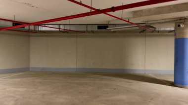 Çok geniş, boş bir yeraltı otoparkı. Temiz çizgiler, parlak yüz hatları ve minimalist tasarım sergiliyor.