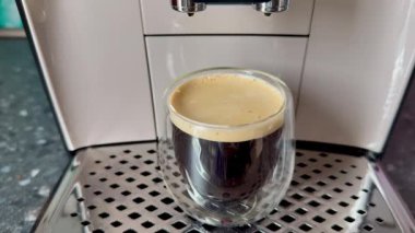 Yüksek kaliteli bir kahve makinesinden gelen cam bardakta servis edilen taze demlenmiş bir espresso.