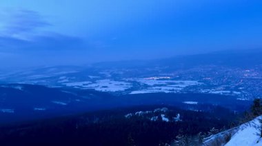 Şehrin akşam manzarası ve gözlem güvertesinden karla kaplı dağlar. Yüksek kalite 4k görüntü
