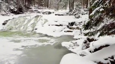 Donmuş bir şelaleyi gözler önüne seren güzel, sakin bir kış manzarası. Etrafı karla kaplı ağaçlarla çevrili.