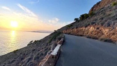 Gün batımında muhteşem bir kayalık yamaçta zarif bir şekilde kıvrılan muhteşem bir sahil yolu.