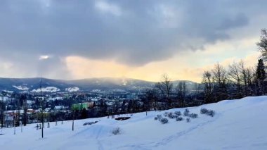 Karla kaplı dağların ve Liberec şehrinin üzerinde gün batımında parlak bir gökyüzü. Yüksek kalite 4k görüntü