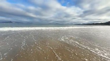 Sakin bir sahil sahnesi yumuşak dalgalar ve dramatik bir akşam gökyüzü, rahatlamak ve gevşemek için ideal.