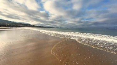 Güzel ve sakin bir sahil manzarası var. Nazik, dalgalı ve inanılmaz bulutlu bir gökyüzü.