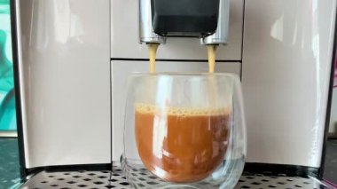 Şık ve modern bir espresso makinesi ustalıkla temiz bir bardağa lezzetli bir fincan kahve dolduruyor.