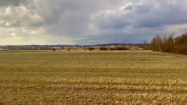 Uçsuz bucaksız bir tarlanın hareketsiz bir görüntüsü dalgalanan bulutlar, sergilenen doğa güzelliği ve tarım arazisi.