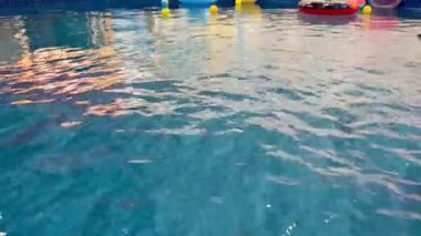 Gün batımında rengarenk şamandıralar ve dalgalı suyla aydınlatılmış güzel bir havuz. Yaz temaları için mükemmel.