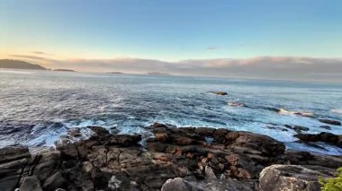 Gün batımında okyanus dalgalarının güçlü bir şekilde kayalık kıyılara çarptığını görmek.