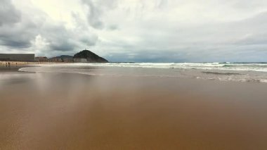 Sakin bir sahil sahnesi, yumuşak dalgalar ve kasvetli bir gökyüzü, rahatlamak ve günlük hayattan kaçmak için mükemmel.