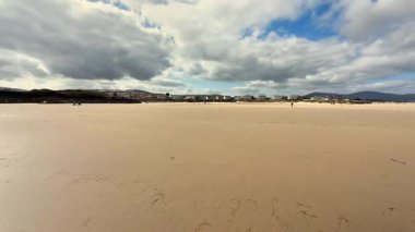 Nefes kesen bir plaj sahnesi, hafif dalgaları tasvir eder canlı, berrak bir mavi gökyüzüne karşı.