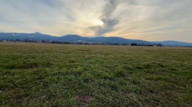Muhteşem dağlarla dolu engin ve açık bir arazinin nefes kesici ve çarpıcı manzarası güzel bir günbatımı gökyüzünün altında.