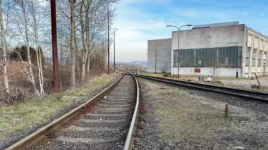 Uzun zamandır kullanılmayan bir sanayi tesisinin yanında uzanan dolambaçlı demiryolu raylarının huzurlu ve huzurlu bir manzarası.