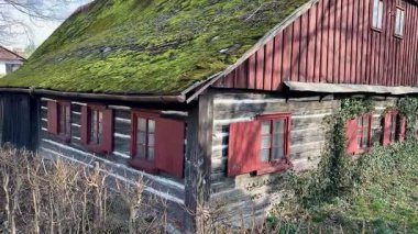 Büyüleyici kırsal bir kulübe, Mossled çatısı ve büyüleyici kırmızı pencereleriyle güzelce süslenmiş.