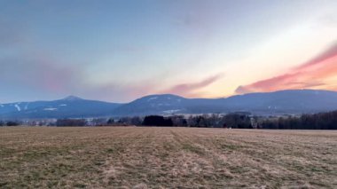 Alacakaranlık saatlerinde yuvarlanan tepelerin nefes kesici manzarası, canlı gökyüzünü ve geniş açık alanları gösteriyor.