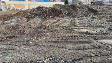 Görüntü, toprak tepecikleriyle birlikte düzensiz ve engebeli bir arazinin olduğu bir inşaat alanının dinamik görüntüsünü yakalıyor.