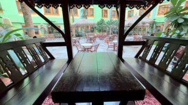 Huzurlu ve sakin bir açık hava yemek alanı. Canlı ve bereketli bir çevrede rahat ahşap koltuklar var.