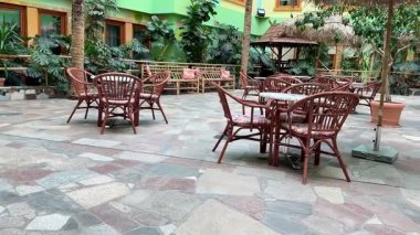 Sessiz ve yemyeşil bir zemine karşı hasır mobilyaları olan büyüleyici bir açık hava yemek alanı.