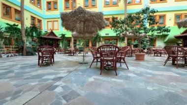 Çimenli bitkilerle süslü, ahşap mobilyaları davet eden, huzurlu bir kaçış sağlayan güzel bir iç avlu.