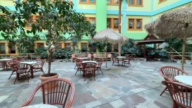 Konforlu oturma alanları, bol yeşillik ve büyüleyici sazdan şemsiyeler içeren canlı ve canlı bir avlu.