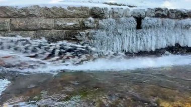 Buz gibi bir şelalenin nefes kesici manzarası engebeli kayaların üzerinden kristal gibi berrak bir nehre dökülüyor.