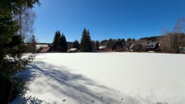 Çok güzel, sakin bir kış manzarası. Engin, karla kaplı bir tarlayı gözler önüne seriyor. Parlak, mavi bir gökyüzünün altında.