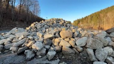 Berrak mavi bir gökyüzünün altında, bereketli ağaçlarla çevrili, nefes kesici manzaralı büyük kayalar.