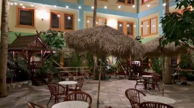 Büyüleyici bir avluda sazdan şemsiyeler, tropikal bitkiler ve herkes için davetkar koltuklar var.