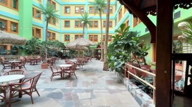 Yeşillik, kırsal mobilya ve canlı parlak renklerle süslenmiş canlı bir avlu.