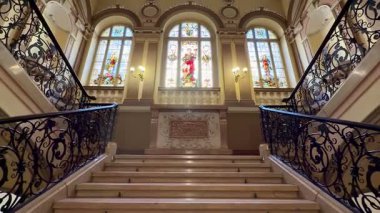 Karmaşık parmaklıklar ve çarpıcı cam pencerelerle süslenmiş görkemli ve görkemli bir merdiven.