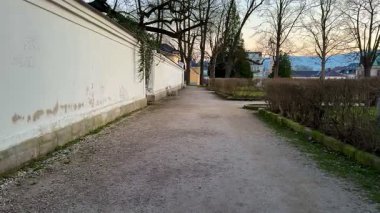 Gün batımında yeşillik ve beyaz bir duvarla çevrili sakin bir yürüyüş yolu. Huzurlu yürüyüşler için mükemmel..