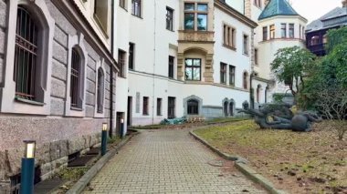 Tarihi yapılar zarif bir şekilde büyüleyici yollar ve canlı yeşillik içeren sakin bir avluyu çevrelemektedir.